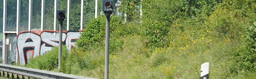 Ein Blitzer am Straßenrand überwacht den Straßenverkehr.