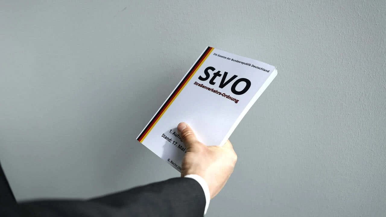 Verkehrsrechtsanwalt hält ein Buch über die Straßenverkehrsordnung in der Hand.