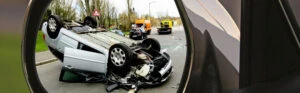 Rückspiegel mit verunfalltem Auto.