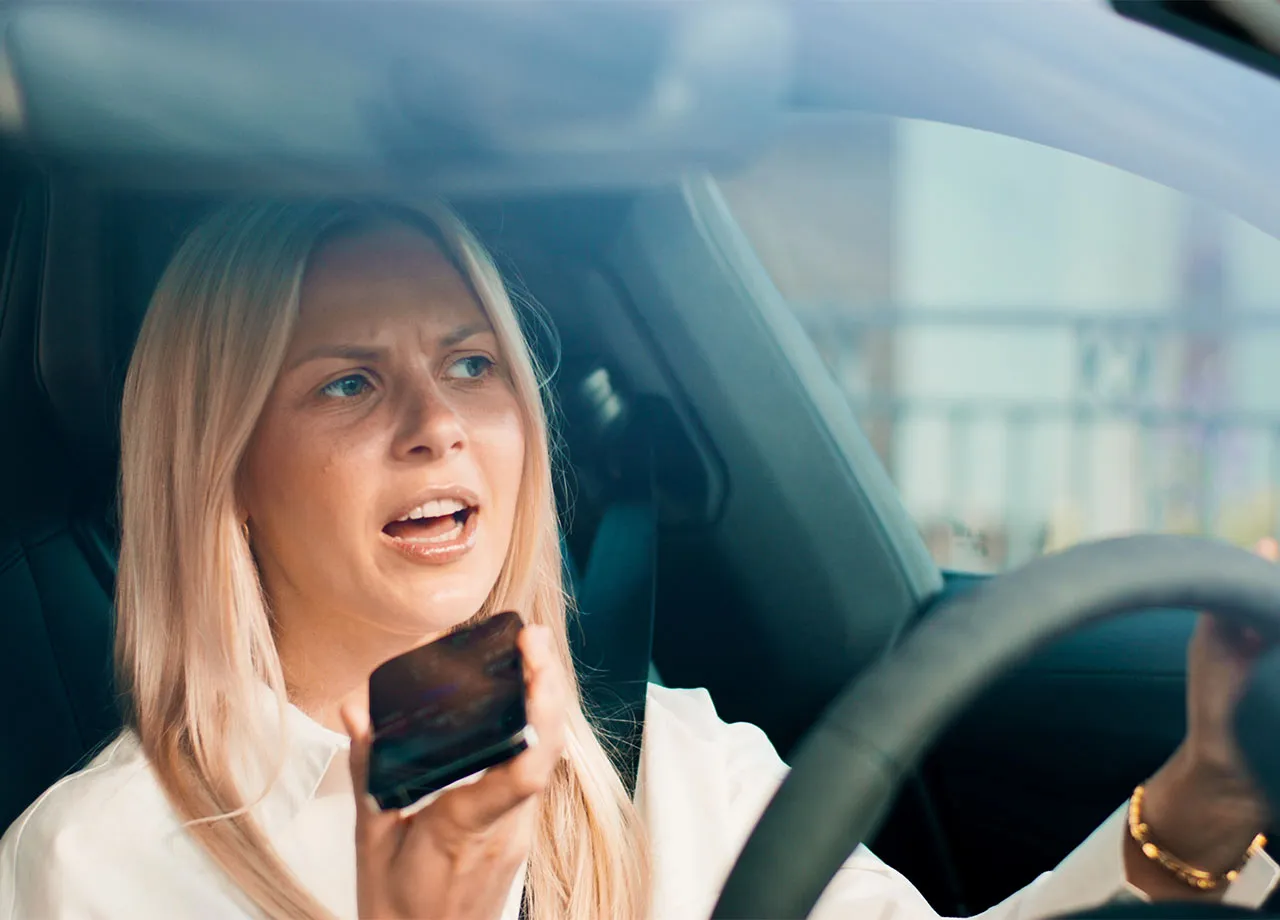Eine junge Frau telefoniert, während sie mit dem Auto fährt.