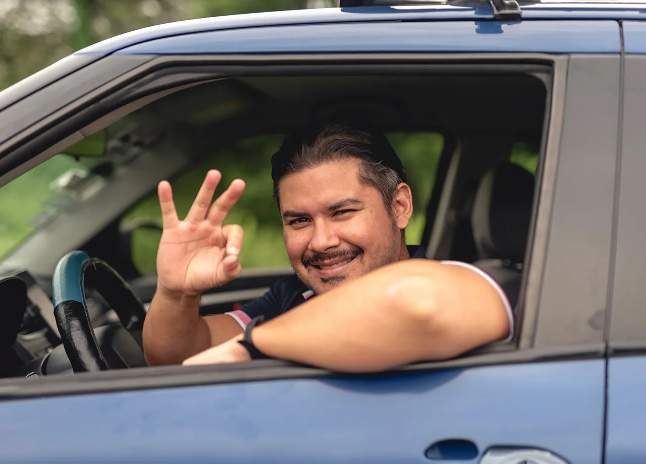 Ein Autofahrer schaut aus dem Seitenfenster und signalisiert: alles okay.